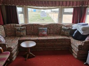 a living room with a couch and a table at Heacham South Beach static caravan in Heacham