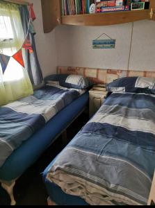 two beds in a small room with a window at Heacham South Beach static caravan in Heacham