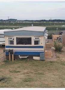 Heacham South Beach static caravan في هيشام: كارافان زرقاء وبيضاء متوقفة في ساحة