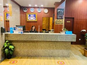 a woman sitting at a counter in a waiting room at Top Hotel Apartments in Al Ain