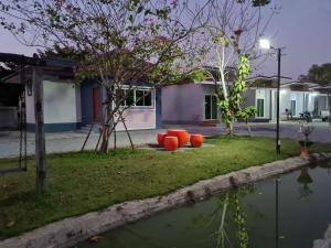 a yard with orange chairs and a body of water at Araya Cottage in Ban Bung Thap Tae (1)