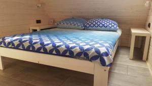 a bed with a blue and white comforter and two tables at Apartamenty Eko Domek in Junoszyno