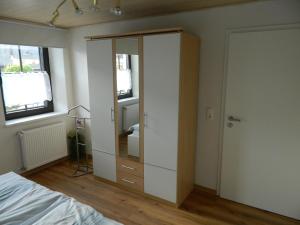 Ferienwohnung Bretz في Dreis: غرفة نوم مع خزانة بيضاء ومرآة