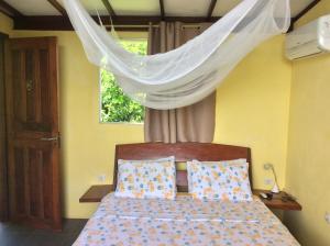 a bedroom with a bed with a canopy and a window at Pousada VillaBahia in Morro de São Paulo