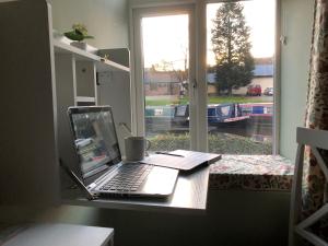 a laptop computer sitting on a desk next to a window at Marina View cottage in Furness Vale