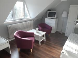 Cette chambre dispose de 2 chaises, d'une table et d'une télévision. dans l'établissement Sára Apartman Parádfürdő, à Parád