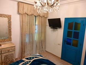 a bedroom with a blue door and a tv at Dar El Kasba Riad Guest House in Bizerte