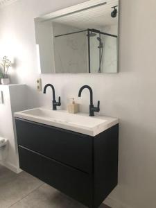 een wastafel in de badkamer met 2 kranen en een spiegel bij Vakantie in Oostende Maison Martha -5 slaapkamers in Oostende