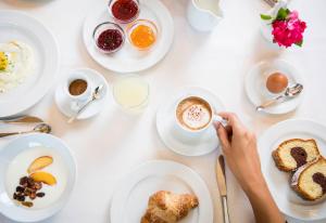 uma mesa com pratos de comida e uma pessoa a beber café em Hotel Weisses Rössl 3Sup em Laion