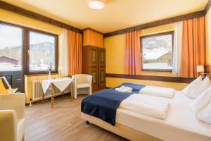 a hotel room with a bed and a table and windows at Ferienhotel Knollhof in Ramsau am Dachstein +51 photos