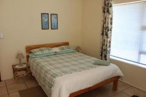 een slaapkamer met een bed en een raam bij Tulip Close in Stilbaai