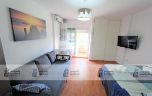 ein Wohnzimmer mit einem Sofa und einem TV in der Unterkunft 102 Estudio en Jupiter Apartmentos - Piscina y Playa - Excelente Ubicación in Benalmádena