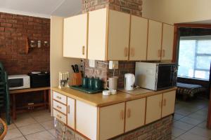 een keuken met witte kasten en een bakstenen muur bij Tulip Close in Stilbaai