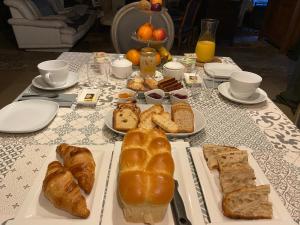 einen Tisch mit Brot, Croissants und anderem Gebäck in der Unterkunft Maison Galimard in Flavigny-sur-Ozerain