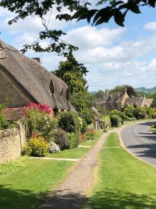 a row of thatched cottages next to a road at Cornerways B&B in Chipping Campden