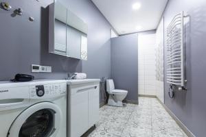 ein Badezimmer mit einer Waschmaschine und einem WC in der Unterkunft VODNA White Apartment in Lwiw
