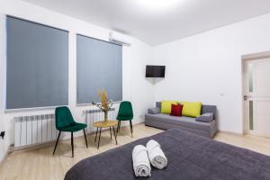 ein Schlafzimmer mit einem Bett, grünen Stühlen und einem Sofa in der Unterkunft VODNA White Apartment in Lwiw