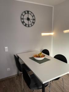 a dining room table with a bowl of fruit and a clock at Ferienwohnung Jasmin in Neustadt an der Weinstraße