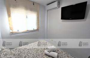 Habitación con cama y TV en la pared. en Apartamento Torremolinos - A 600m de la playa de La Carihuela - PISCINA - PARKING GRATIS - EXCELENTE CONEXIÓN WIFI, en Torremolinos