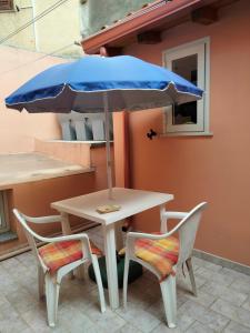 een tafel met een blauwe parasol en twee stoelen bij Casa Maglad in Noto