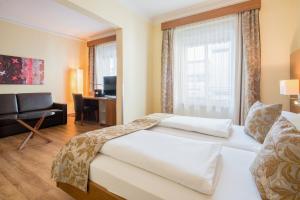 a hotel room with two beds and a desk at Hotel Weißes Kreuz in Bregenz