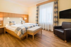 a hotel room with a bed and a chair at Hotel Weißes Kreuz in Bregenz