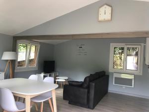 uma sala de estar com uma mesa, um sofá e um relógio em Le Balcon d’Echery em Sainte-Marie-aux-Mines