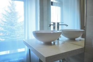 ein Badezimmer mit zwei Waschbecken auf einer Theke mit einem Fenster in der Unterkunft Hotel Voskresensky in Sumy