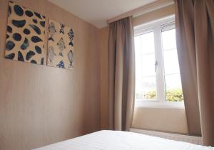 a bedroom with a bed and a window at Chaletpark Krabbenkreek Zeeland - Chalet 150 in Sint Annaland