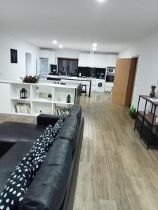 a living room with a black couch and a kitchen at casa do mestre in Vieira do Minho