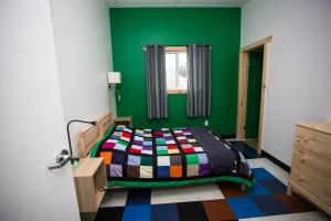 Dormitorio verde con cama y ventana en Out East Adventure Centre, en Rocky Harbour