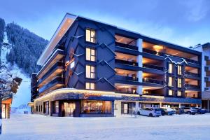 duży budynek z samochodami zaparkowanymi na śniegu w obiekcie Active Nature Resort DAS SeeMOUNT w mieście See