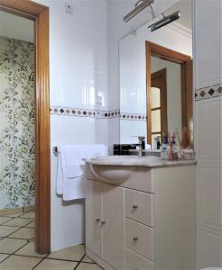 a white bathroom with a sink and a mirror at Luminoso y Moderno in O Grove