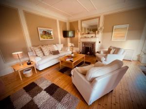 Sandhill House في ترون: غرفة معيشة مع كنبتين بيضاء ومدفأة