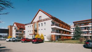 a large white building with cars parked in a parking lot at Apartma Rakita in Moravske Toplice