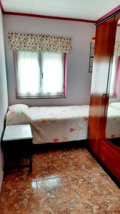 um pequeno quarto com 2 camas e uma janela em Apartamento en San Juan de L'arena em San Juan de la Arena