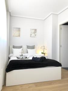 biała sypialnia z dużym białym łóżkiem z czarnym kocem w obiekcie Apto Vistas Mar y Monte Céntrico Garaje Incluido w mieście Castro-Urdiales