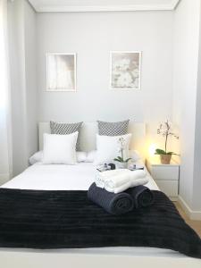 ein Schlafzimmer mit einem weißen Bett und Handtüchern darauf in der Unterkunft Apto Vistas Mar y Monte Céntrico Garaje Incluido in Castro-Urdiales
