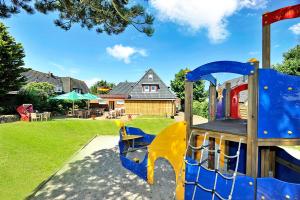 - une aire de jeux dans une cour avec une maison dans l'établissement Hotel und Restaurant Petit Robby, à Wenningstedt