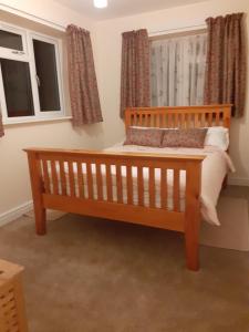 a wooden bed in a room with two windows at Station Retreat 6B Comberton Terrace in Kidderminster