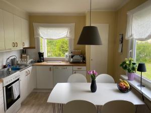 uma cozinha com uma mesa branca com cadeiras e um vaso de flores em Villa Movägen • Fast Free Wifi • AC • 10 min from lake em Mörlunda