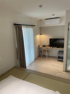 Zimmer mit einem Bett, einem Schreibtisch und einem TV in der Unterkunft DayBreak 2 in Taitung