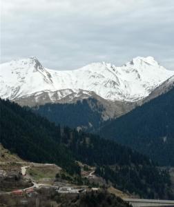 Une montagne enneigée avec une ville en face dans l'établissement Κάλλος-Kallos Apartment, à Metsovo