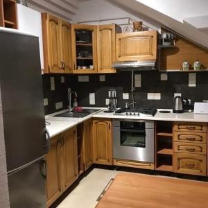 uma cozinha com armários de madeira e um frigorífico de aço inoxidável em Затишна квартира в спальному районі em Lviv