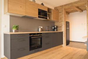 una cocina con electrodomésticos grises y armarios de madera en Ferienwohnung am Dorfbach en Rettenberg