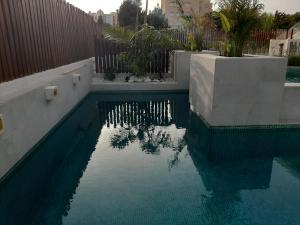 basen z niebieską wodą przed płotem w obiekcie Alaïa Apartamentos w mieście Playa Paraiso