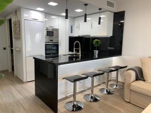 a kitchen with a black and white counter and stools at Formentor in Castelldefels