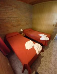 two beds in a room with red sheets at Complejo Arco Iris in Villa Cura Brochero
