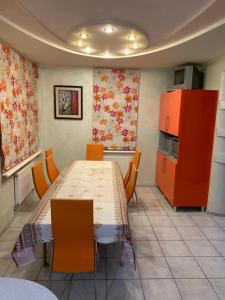 a dining room with a table and orange cabinets at Приватний будинок з сауною та більярдом in Khashchevoye