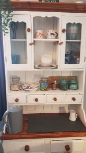 a white cabinet with plates and dishes in it at Post Office Row Apartment and garden in Crickhowell